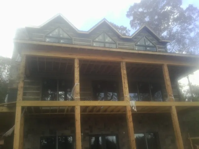 Dormers and porch framing on a large log home under construction — Roof Coating work by our crew in Providence