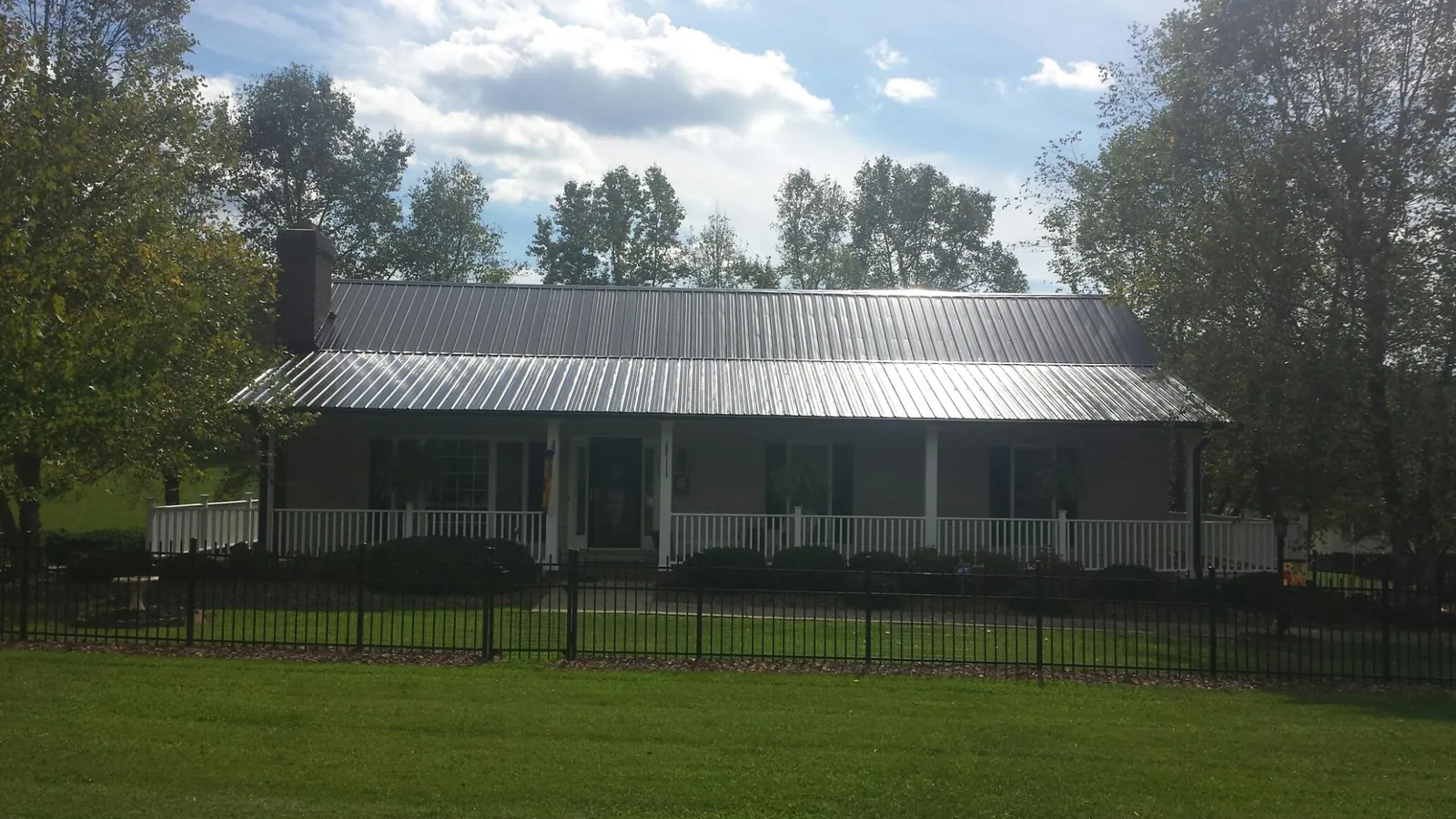 Gray metal roof on a brick ranch with a full width front porch — Gutter Guard Installation work by our crew in Providence
